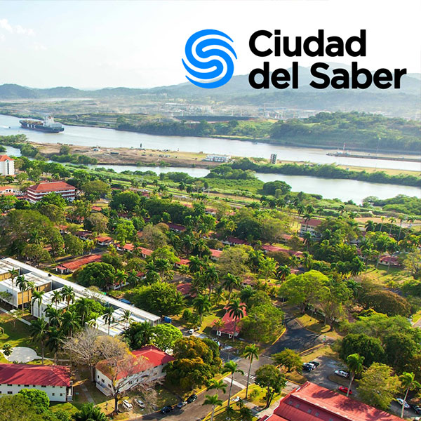 Aerial view of a lush campus with red-roof buildings near a river and canal, with the “Ciudad del Saber” logo in the top-right corner.