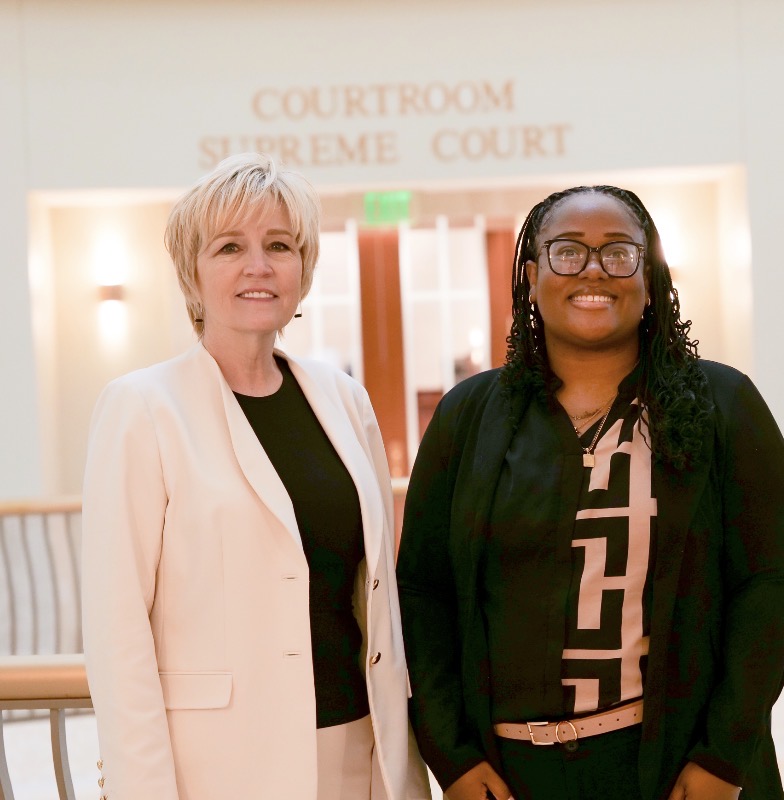 Andrea Reddick and an individual posing in front of a Supreme Court courtroom. 