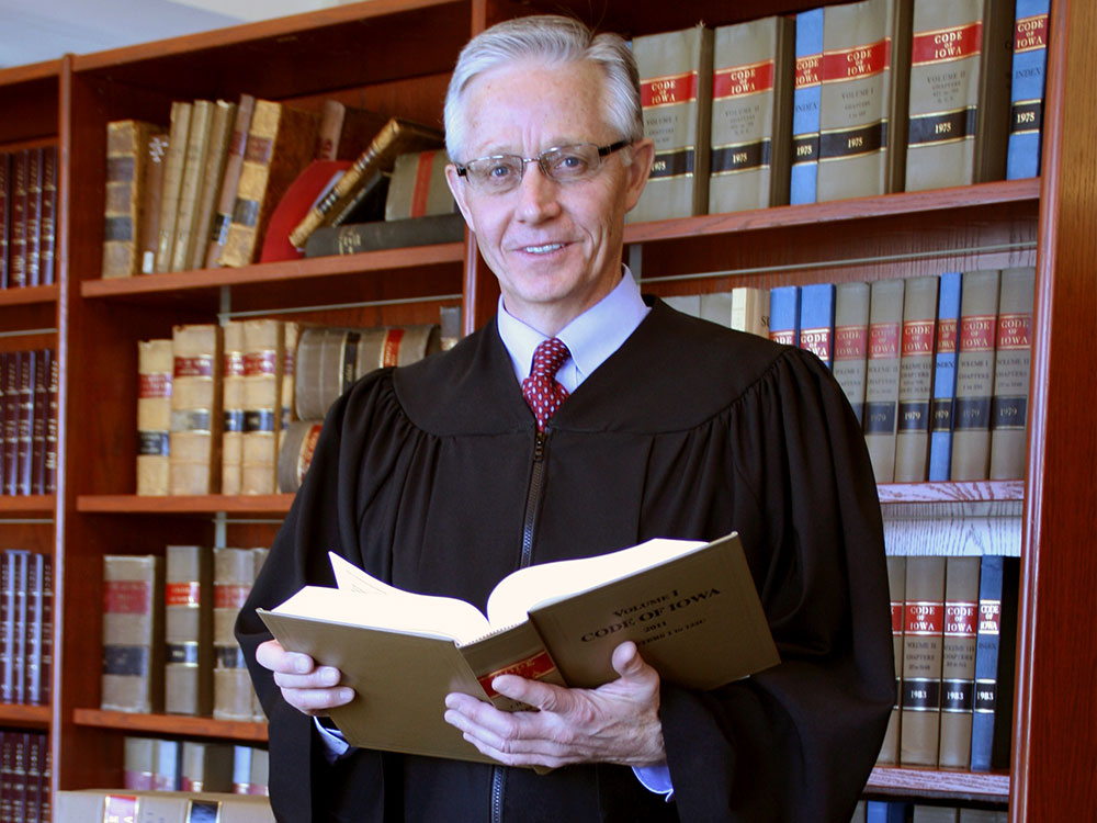 Mark S. Cady holding an open book in a law library