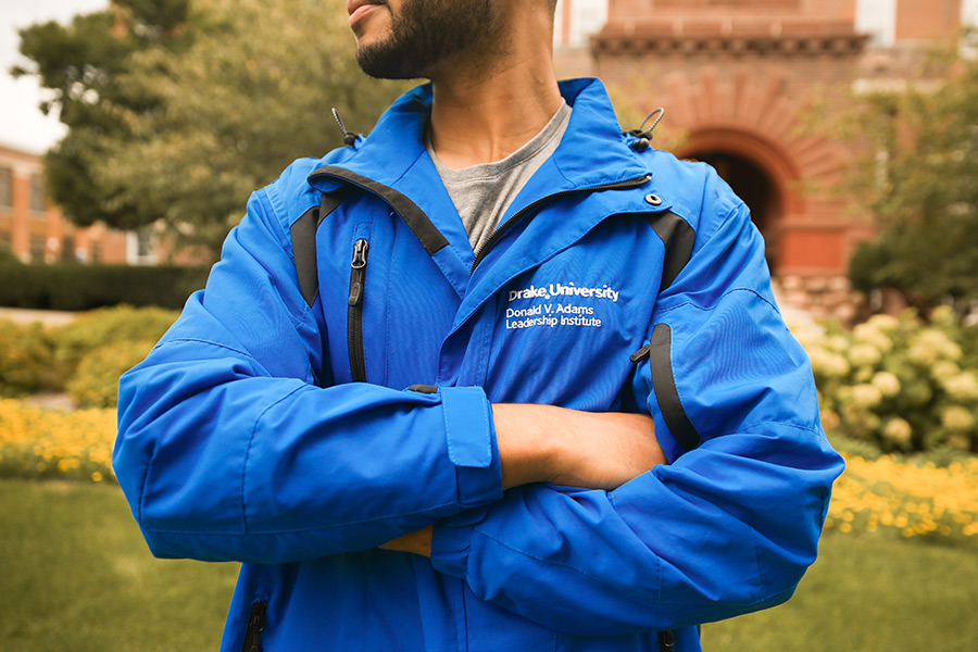 Student standing in front of Old Main with an Adams Leadership Institute blue jacket.