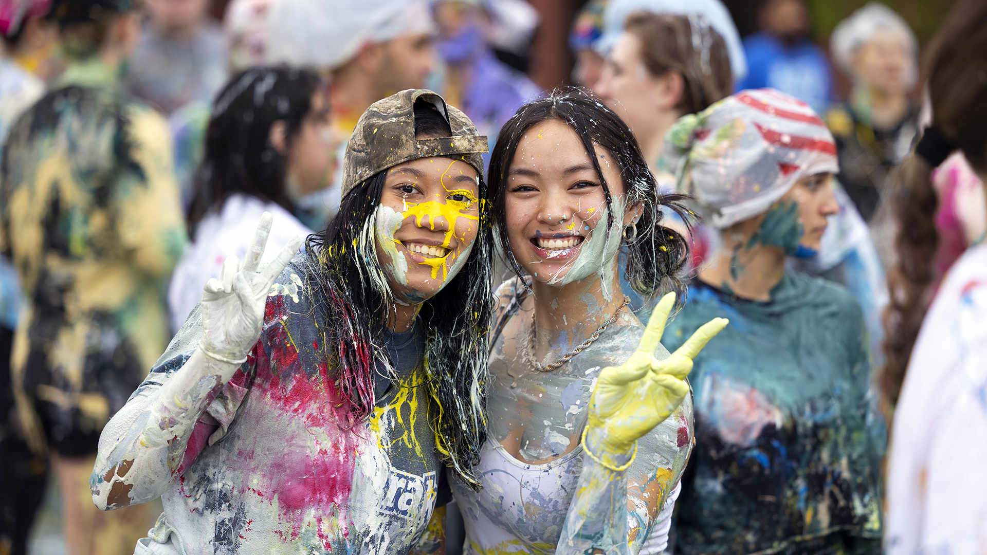 Two Drake University students smile and make peace signs during a campus Holi event