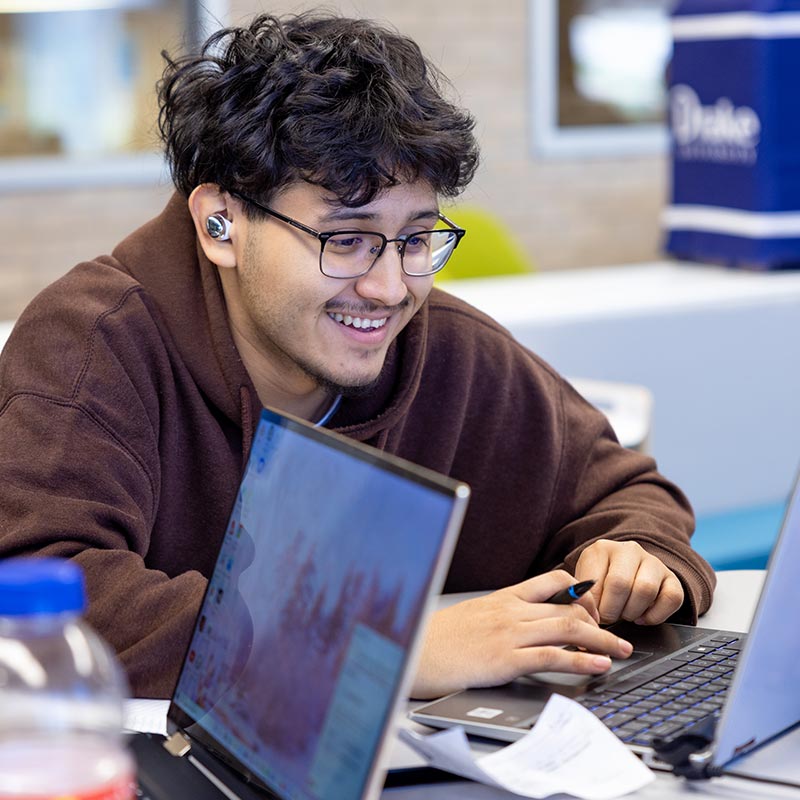 Student smiling while looking at a laptop.