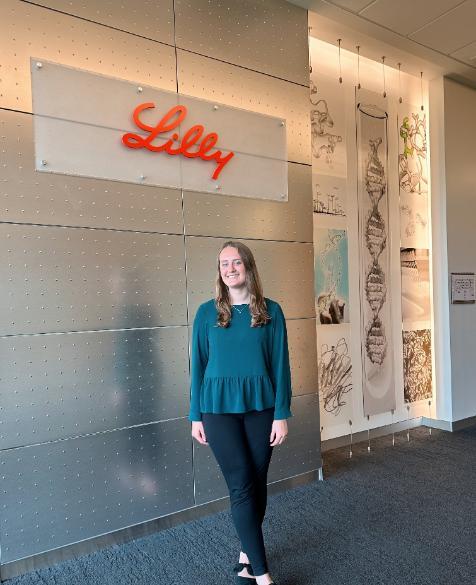 Photo of PharmD Candidate 2024 Ali Goldensoph standing inside Eli Lilly and Company headquarters under a light-up