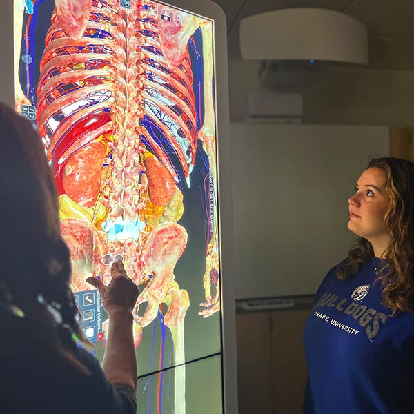 Drake University Instructor showing a female student a view on the Anatomage table.