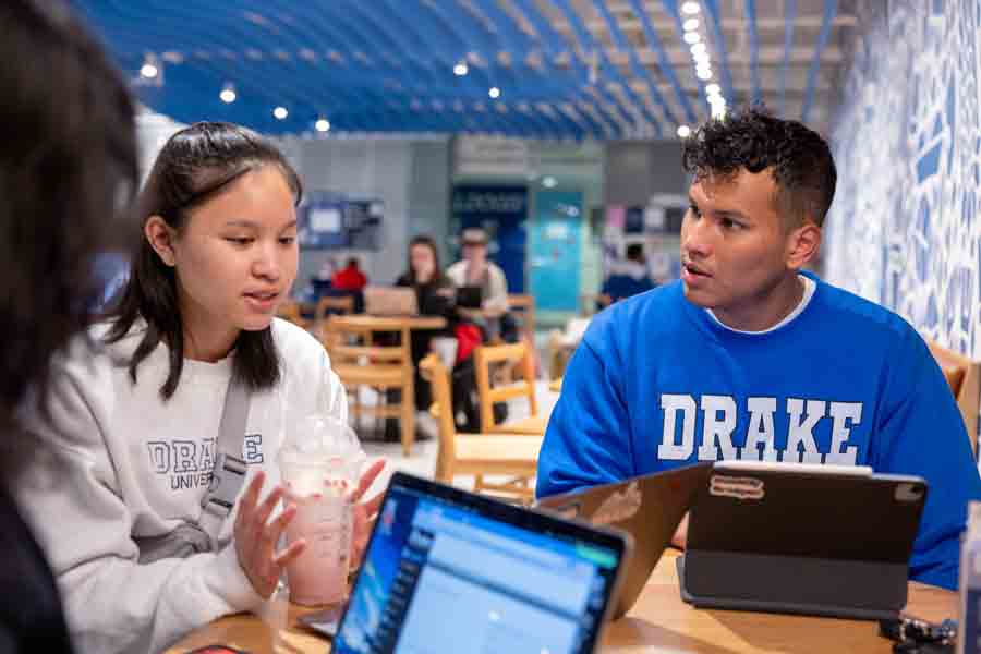 A student speaks to others while sitting at a table on campus