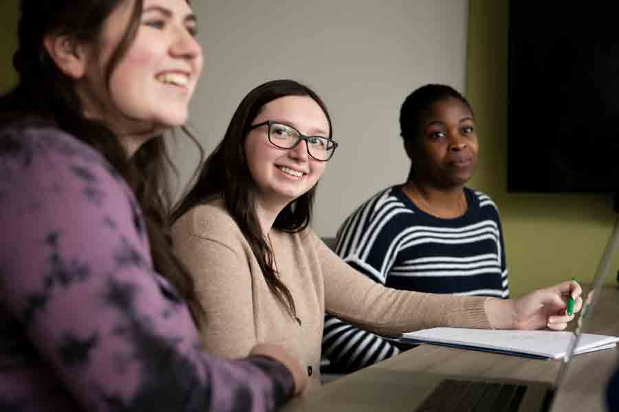 Three students sit at a table smiling