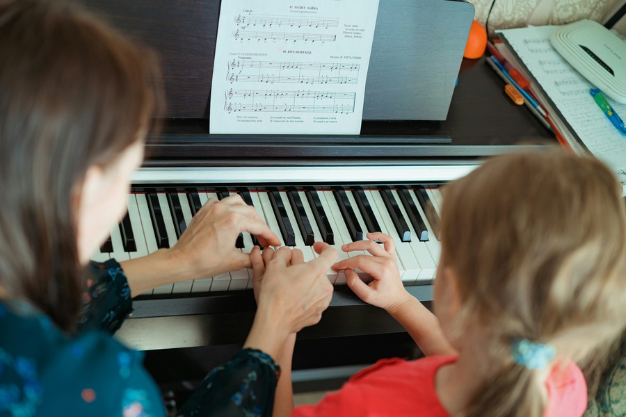 An educator teaches a student the piano