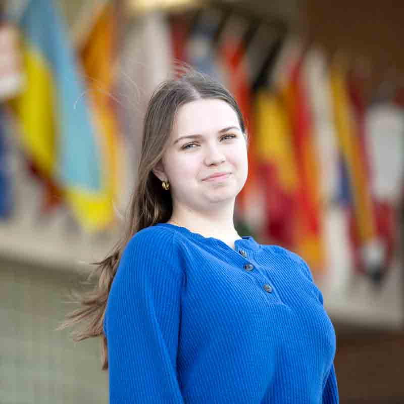 A Drake student stands in front of a row of flags