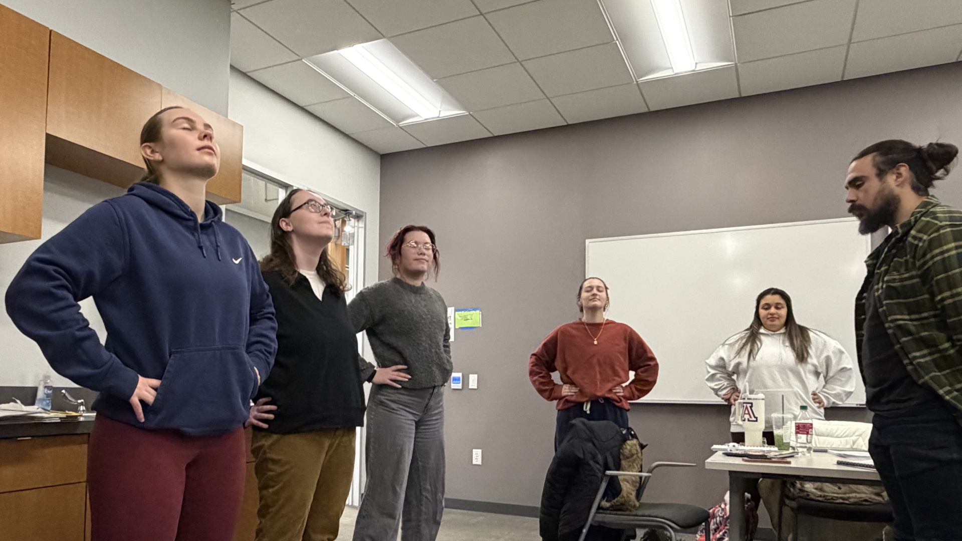 Six counseling students standing in a power pose with their eyes closed, practicing mindfulness