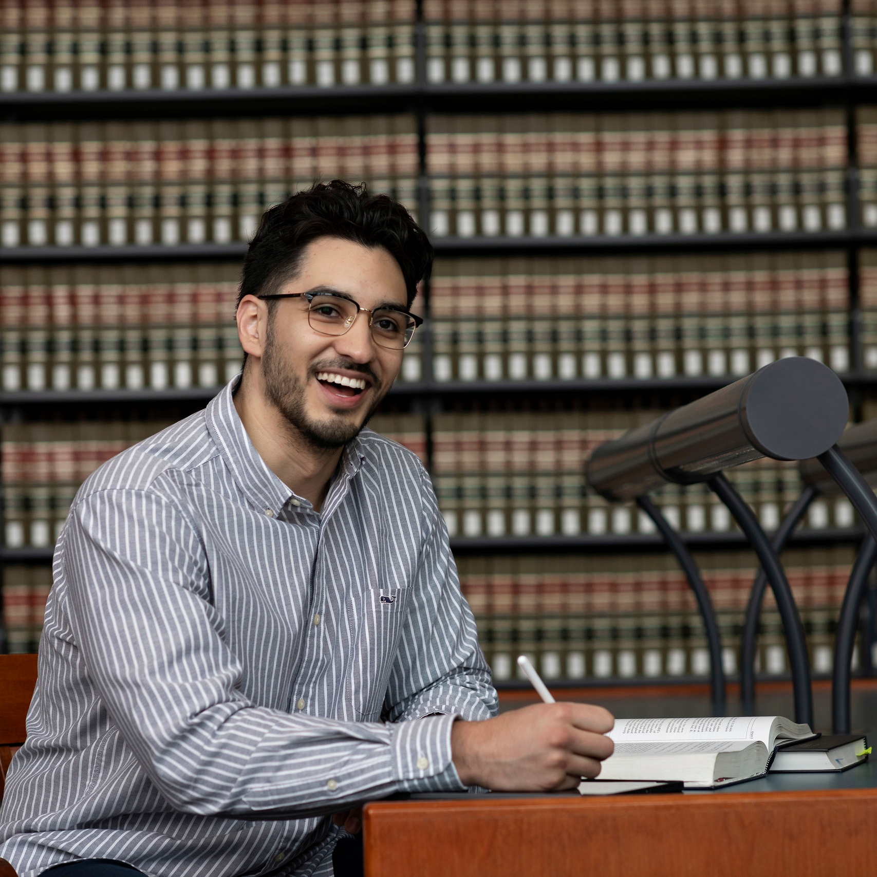A student from Drake's Journalism/Law 3+3 Law program smiles while working on an assignment in a campus law library