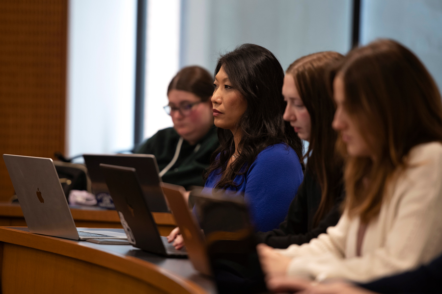 From behind a classroom desk, Drake Journalism students lean forward during a lecture during one of their introductory law classes