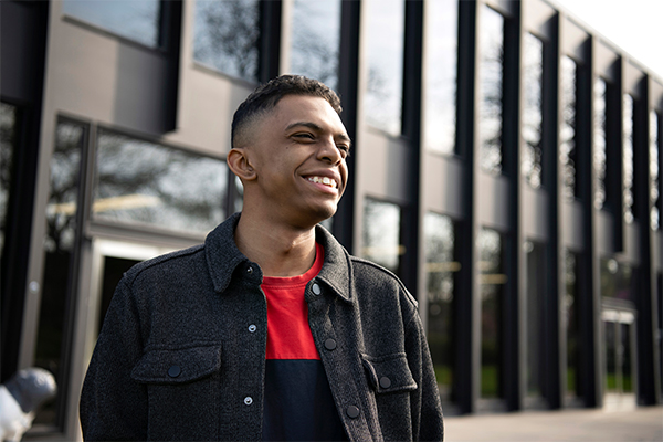 A student enrolled in Drake's A.A. in Integrated Arts, Sciences, and Humanities program stands in front of a classroom building