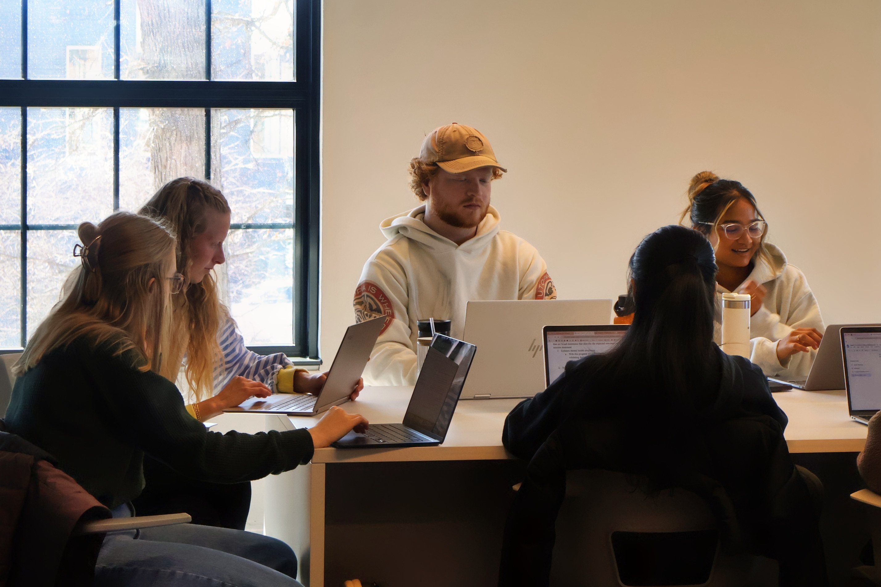 Drake ABSN students study data on laptops while sitting around a table