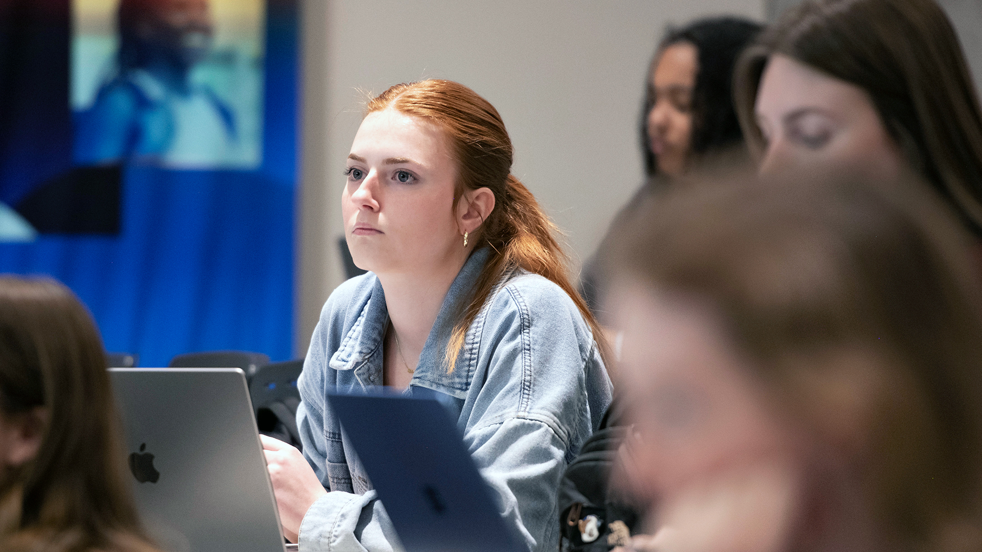Drake Accounting Majors lean forward during a class discussion while taking notes with their laptops