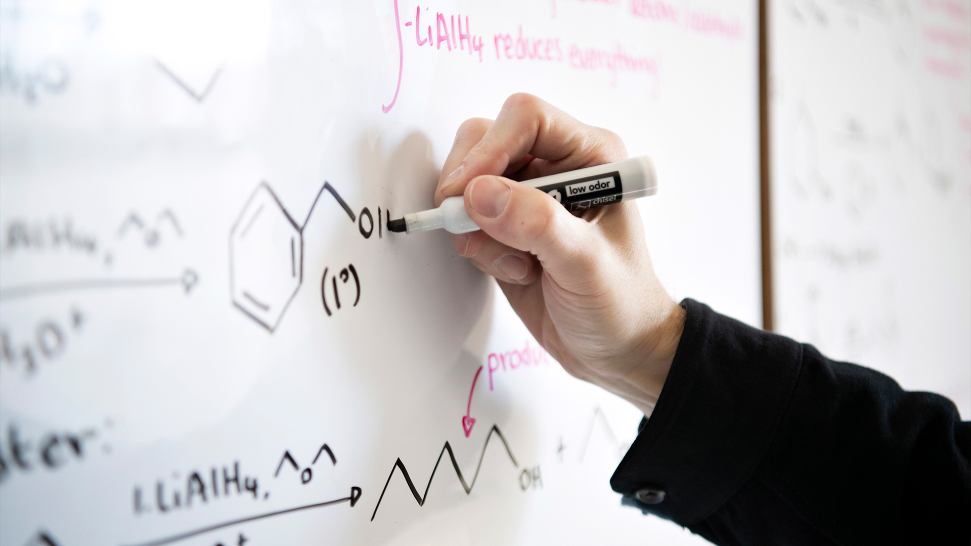 An Actuarial Science Minor at Drake writes an equation with a marker on a whiteboard