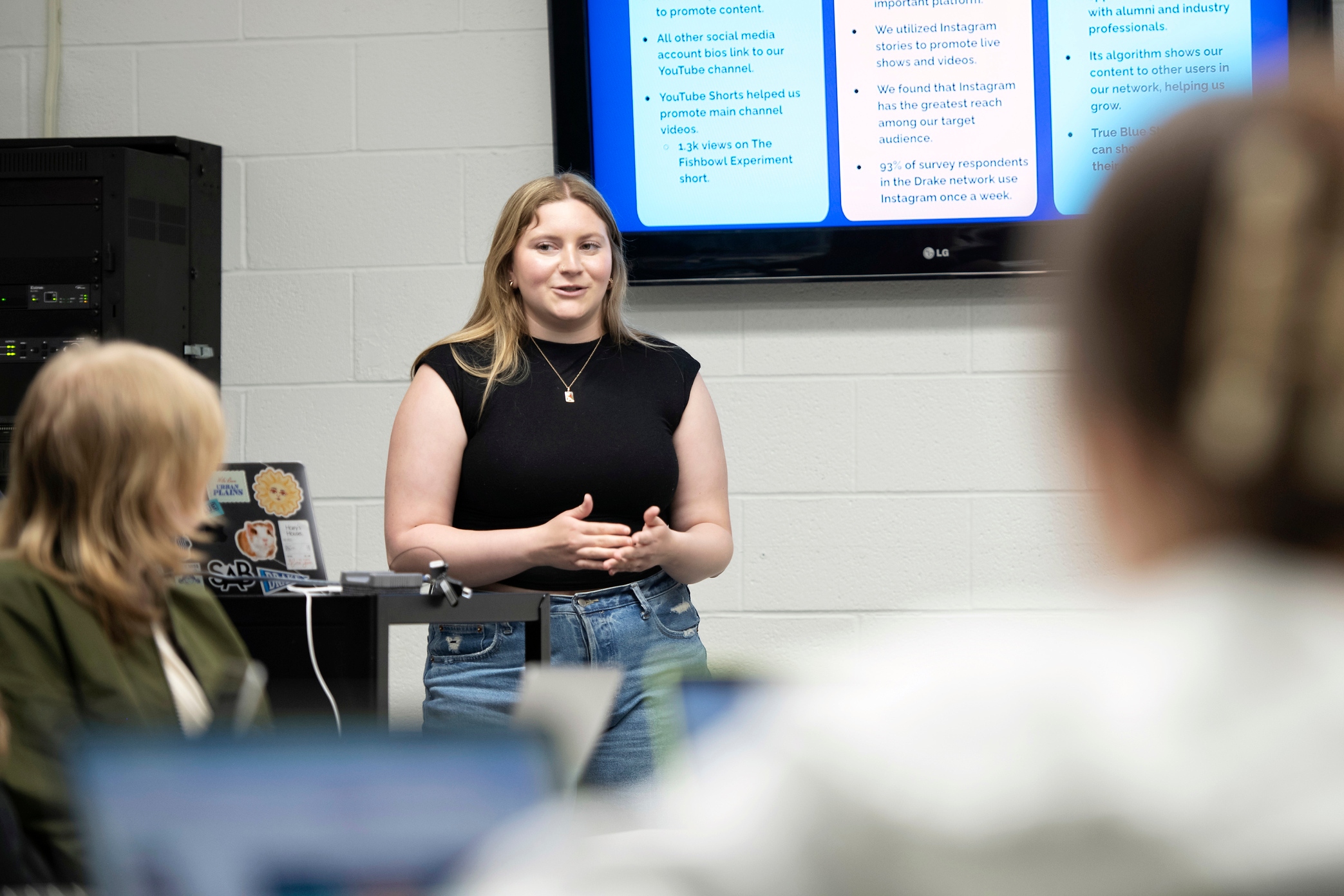 Standing in front of a slide presentation, an advertising professional explains what they do to a classroom of Advertising Majors at Drake University