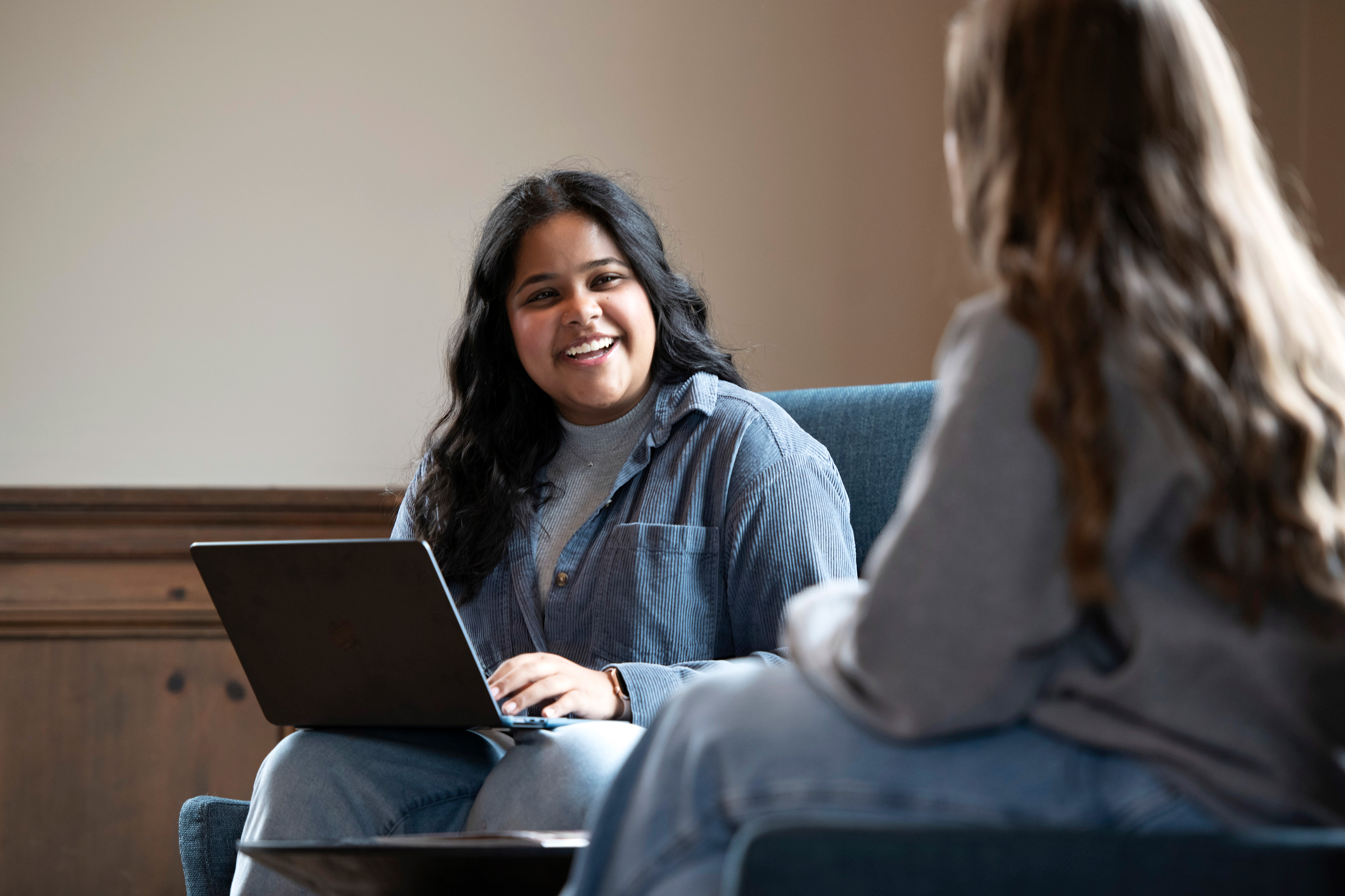 Two Drake Anthropology and Sociology majors converse on a couch in a common area about an assignment