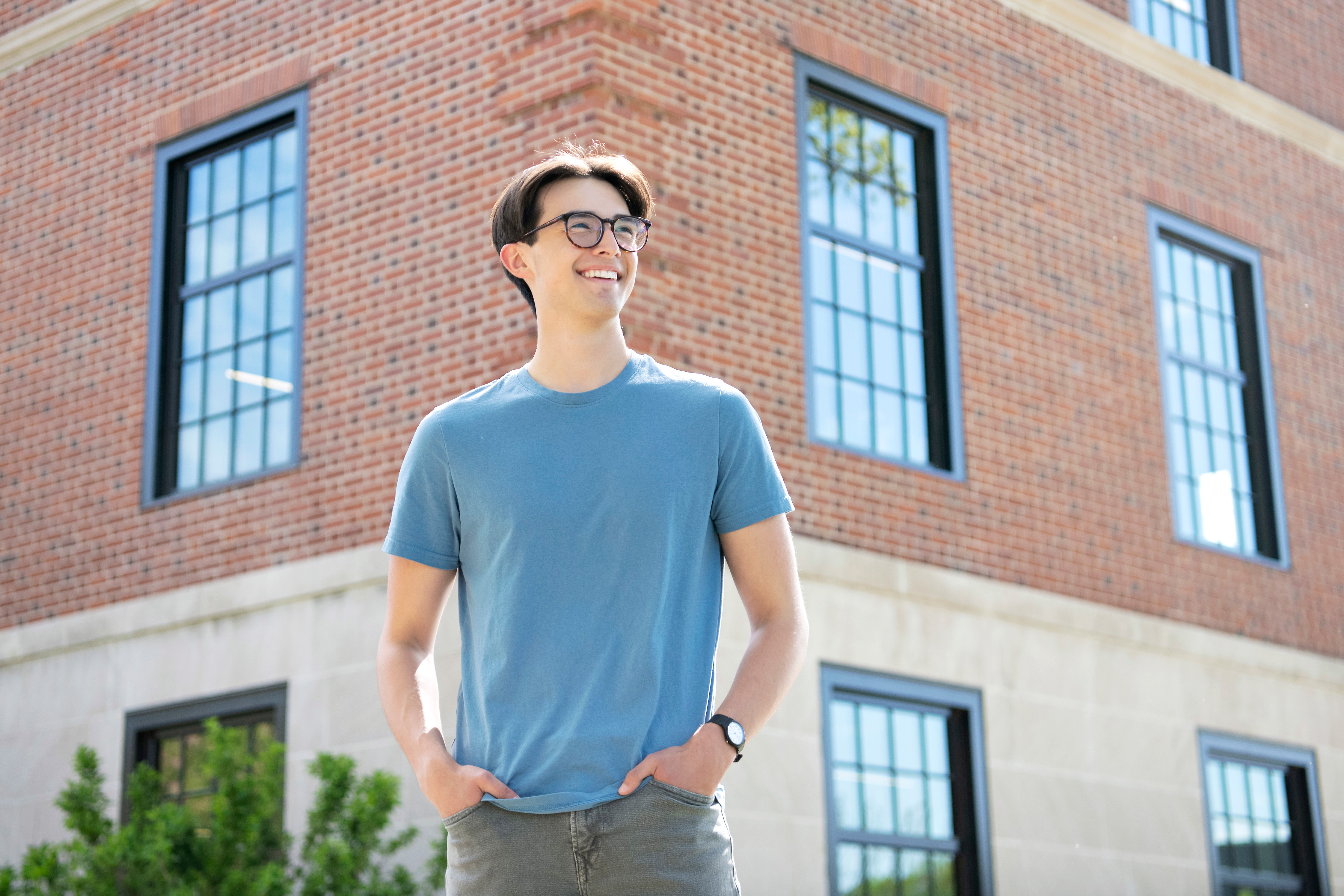 A Drake Anthropology and Sociology majors stands smiling outdoors with their hands in their pockets
