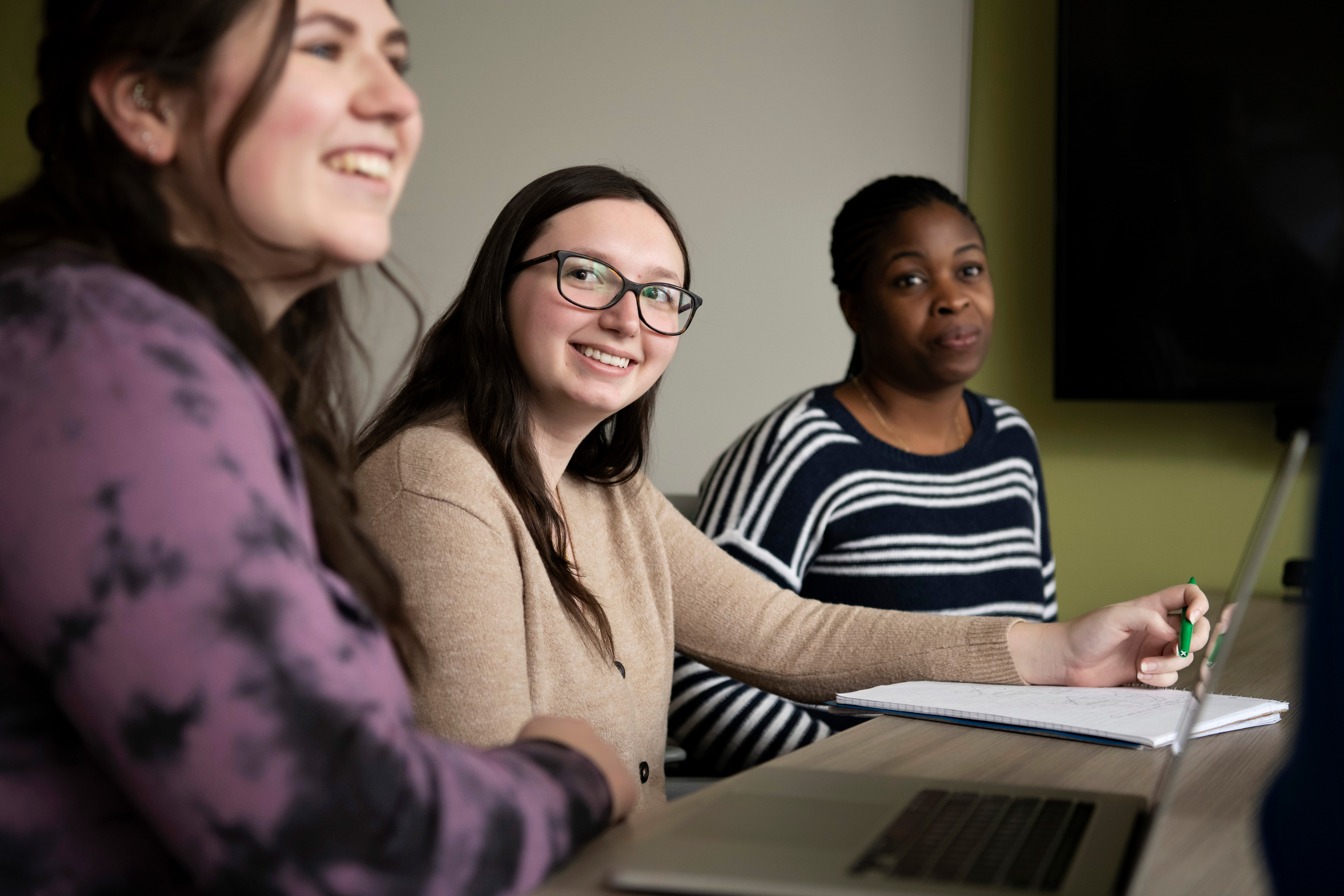Three Drake Anthropology and Sociology students sit along a table for a club meeting