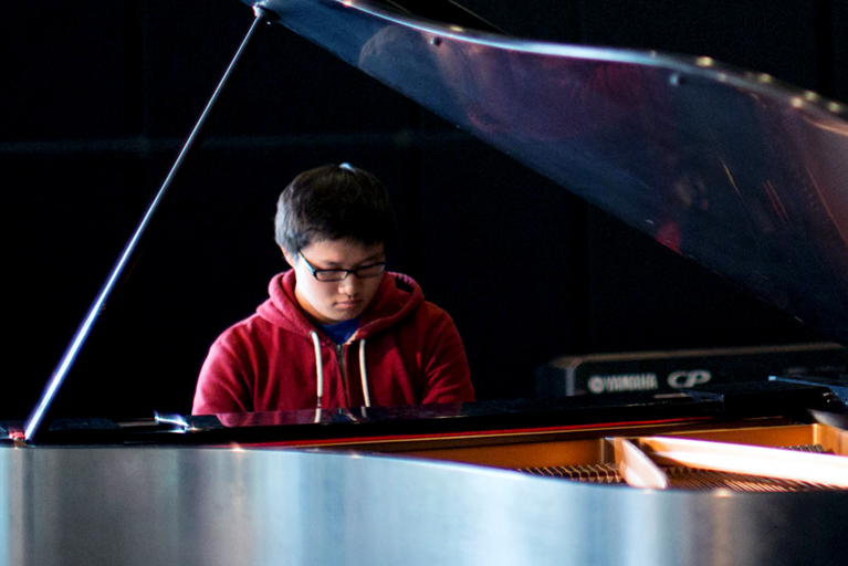 A piano major at Drake practices on a grand piano in a campus auditorium