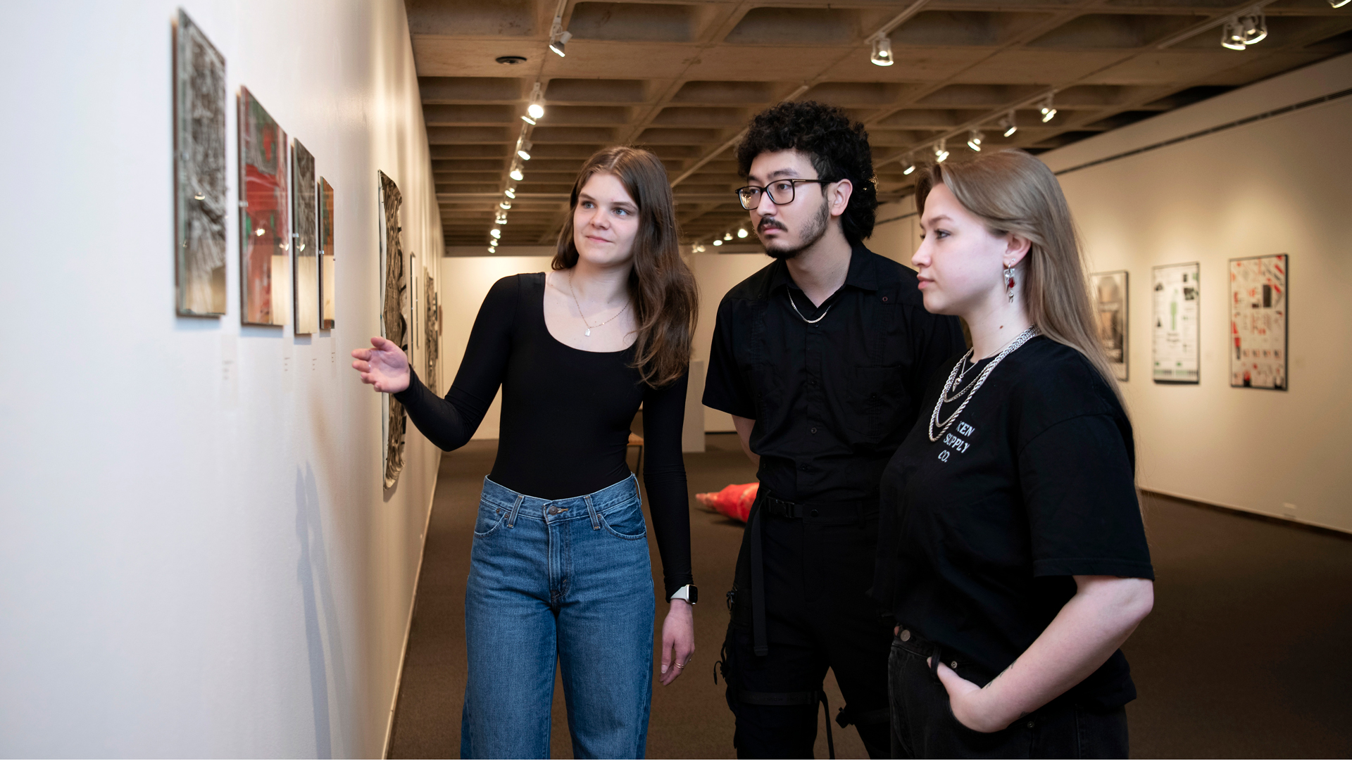 Three Art History students study works in one of Drake University's art galleries