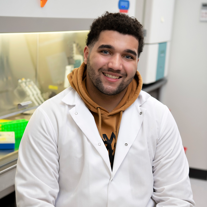 A Drake Biology student wears a hoodie under their lab coat in a campus lab