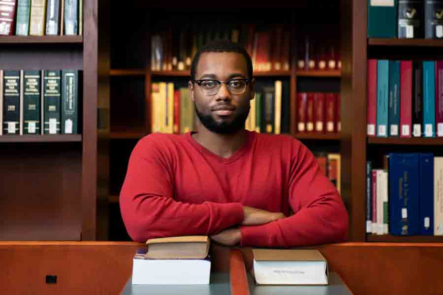 A student from Drake's Black Diaspora Studies program crosses their arms while sitting in a library
