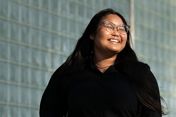 A Drake Business Law student smiles while looking away from a glass brick building