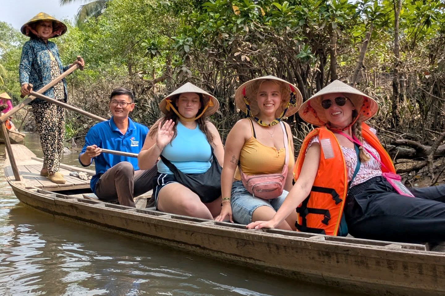 Drake business students in conical hats take a guided canoe ride during a study abroad trip