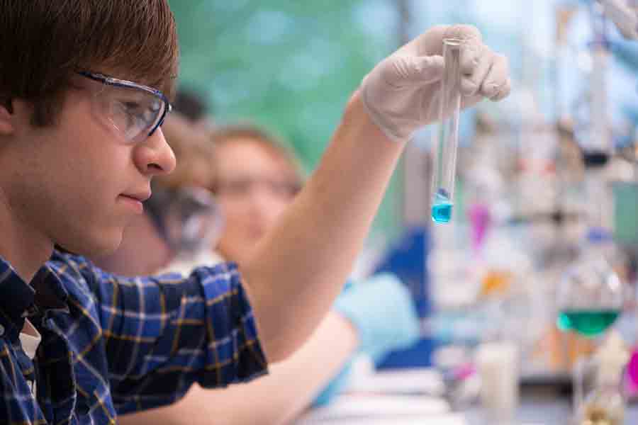 A Drake Chemistry student wearing safety glasses handles a test tube containing a blue liquid