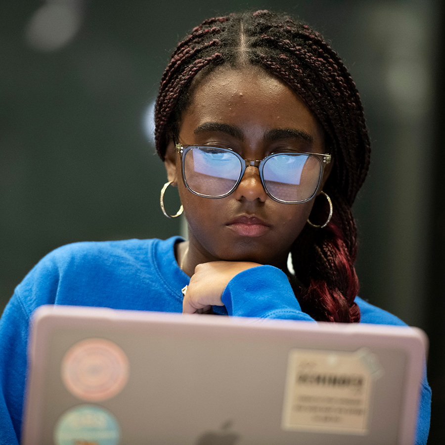 A student from Drake's Computer Science program reviews information on a laptop, with their glasses reflecting the screen
