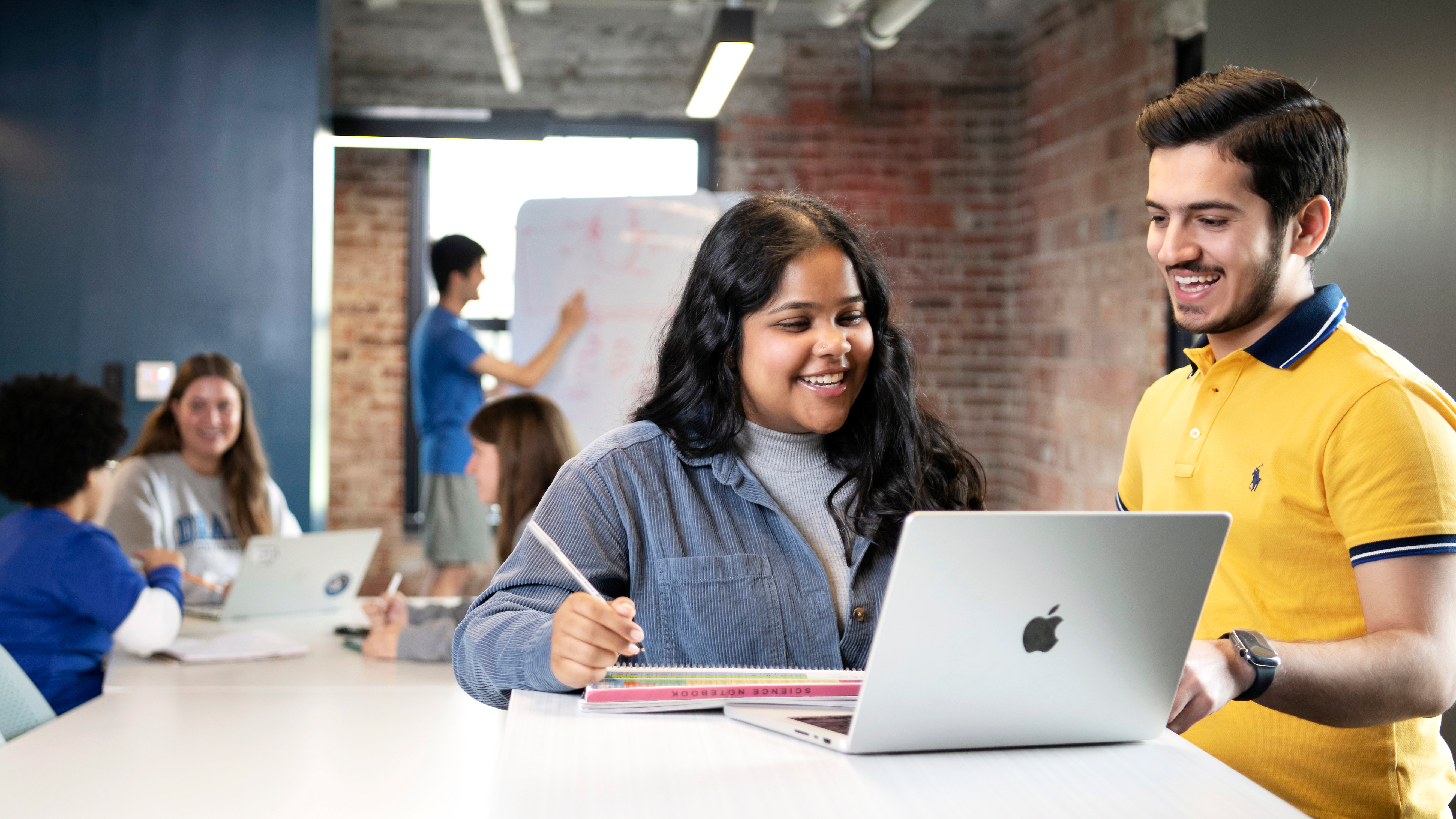 Computer Science students at Drake University huddle around laptops as they work on assignments