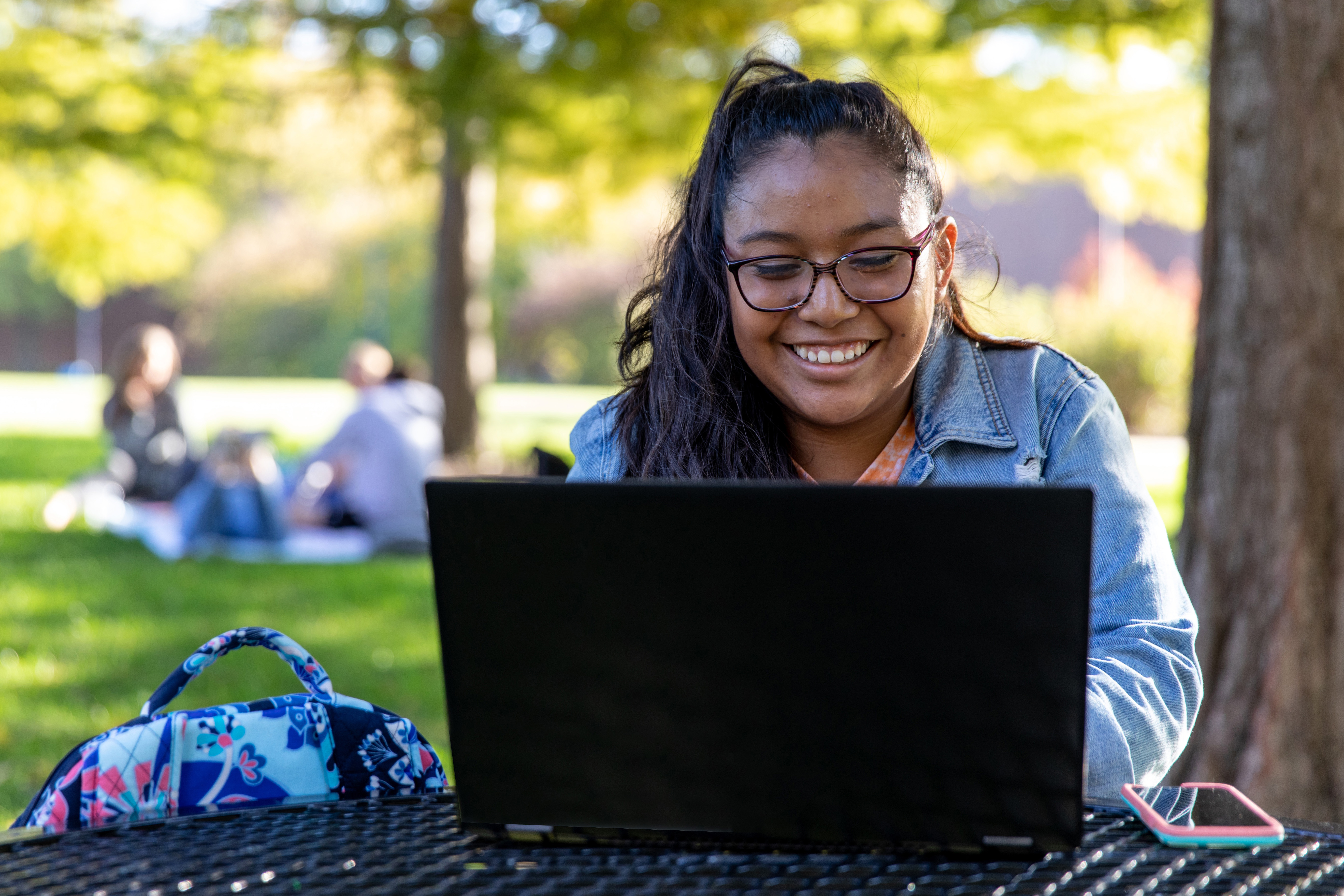 Working on a laptop, a Drake Computer Science students focuses on their independent study project outdoors