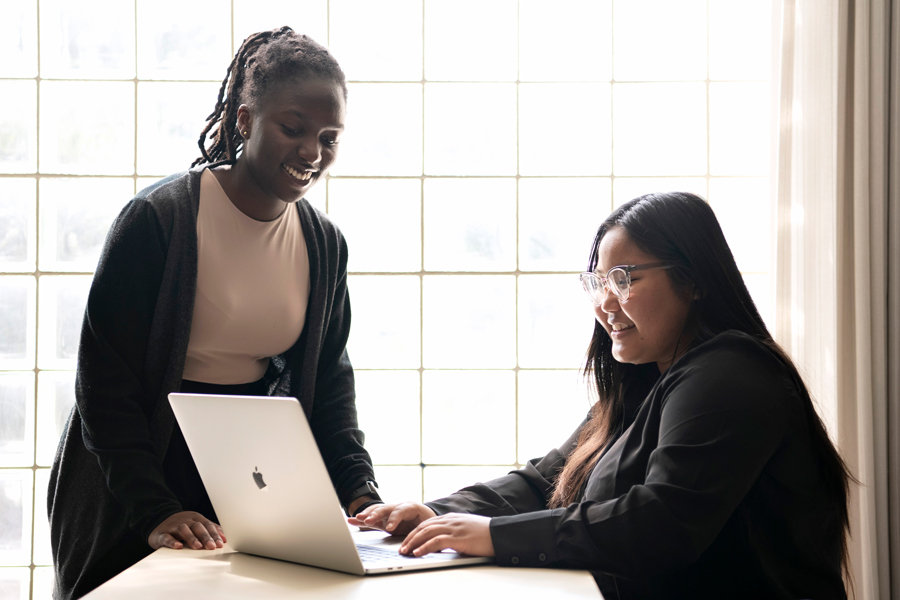 Two Drake Creative Writing students discuss an assignment while standing around a laptop in a common area