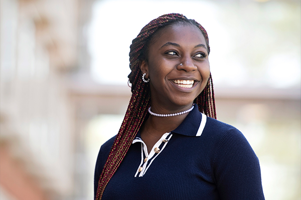 A Drake Economics major in a shirt with a striped collar and gold buttons looks to the left