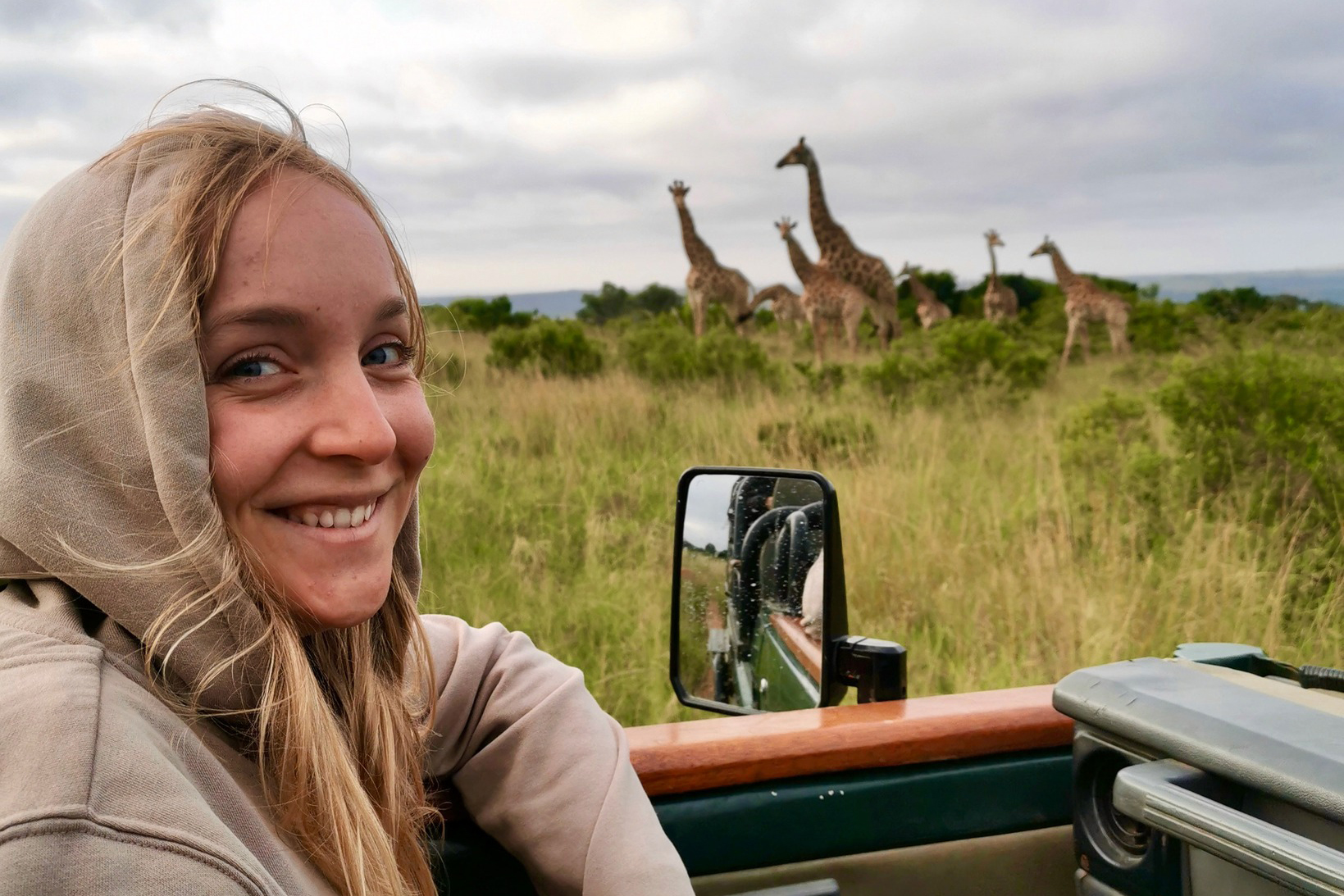 A Drake Environmental Science student sitting in an open-top vehicle observes giraffes at a distance during a study abroad trip