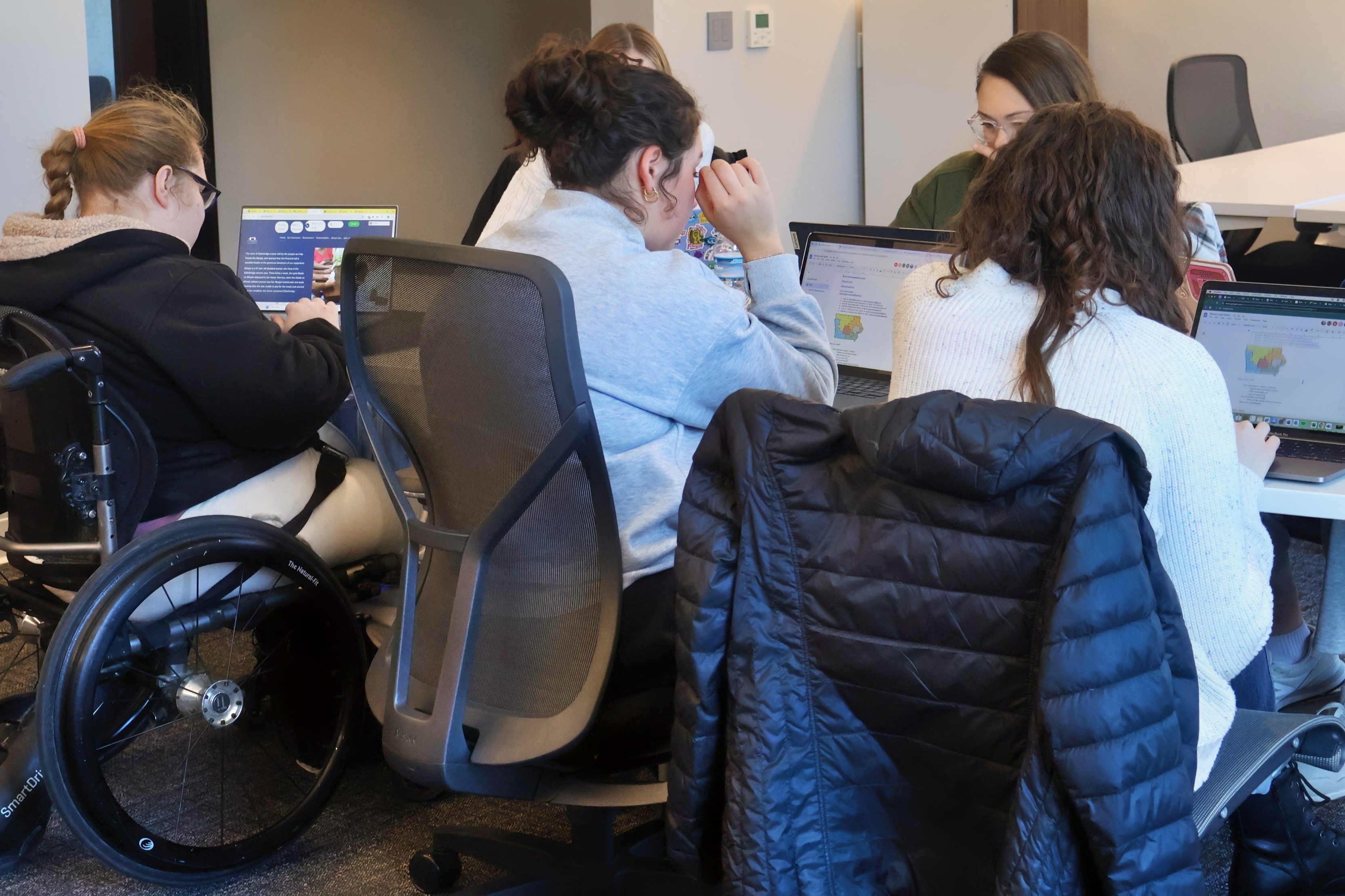 A group of Drake Global and Comparative Public Health students examine data from laptops around a table