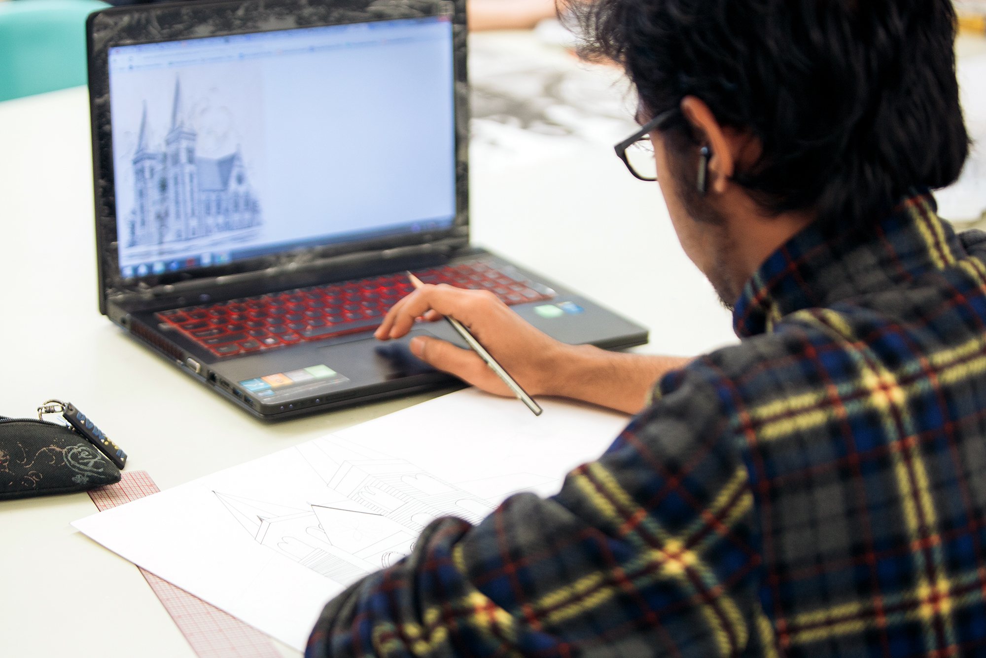 A Drake Graphic Design student works on an assignment featuring a drawing of a house from their laptop
