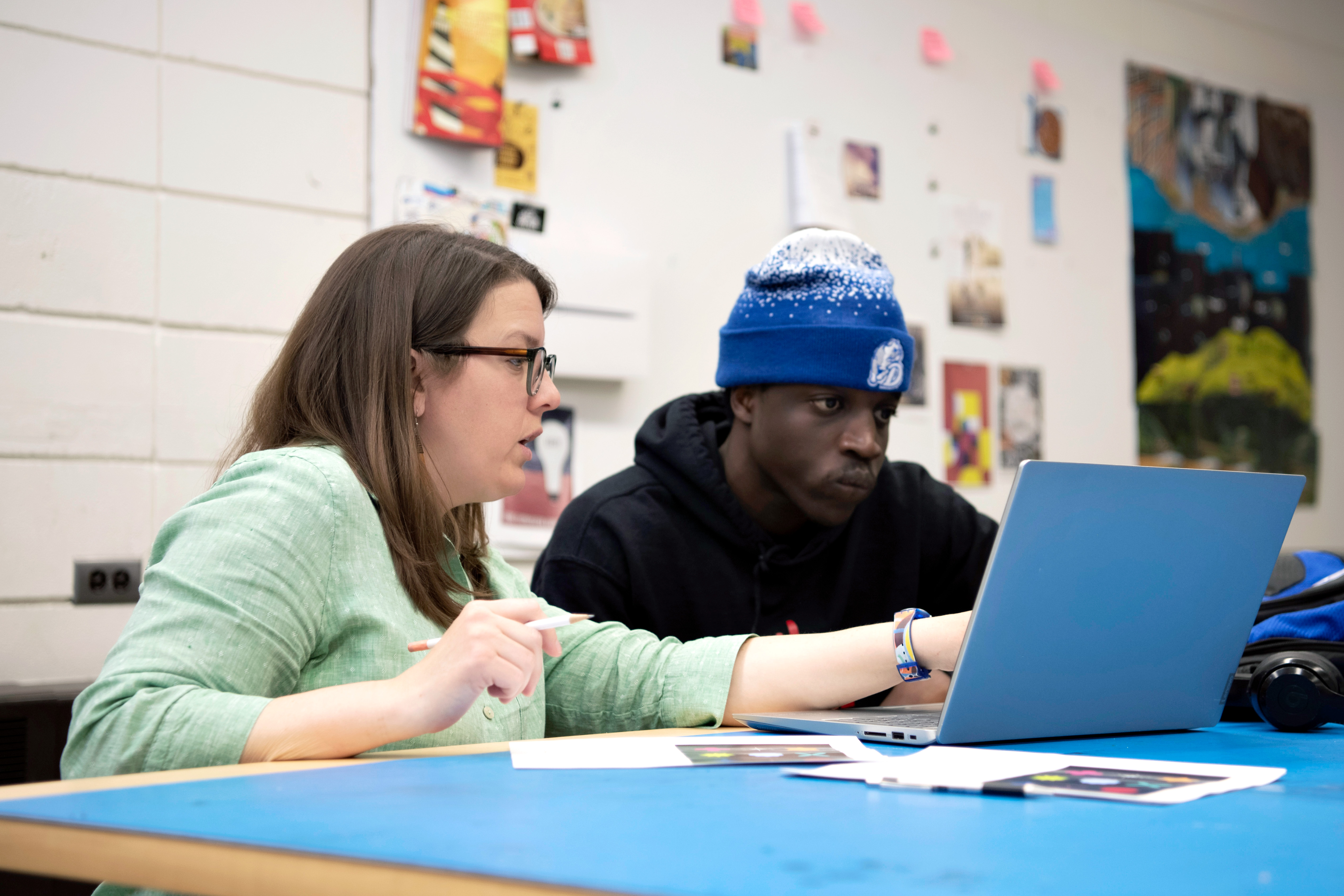 Pointing to a laptop screen, a Drake Graphic Design professor guides a student through an assignment