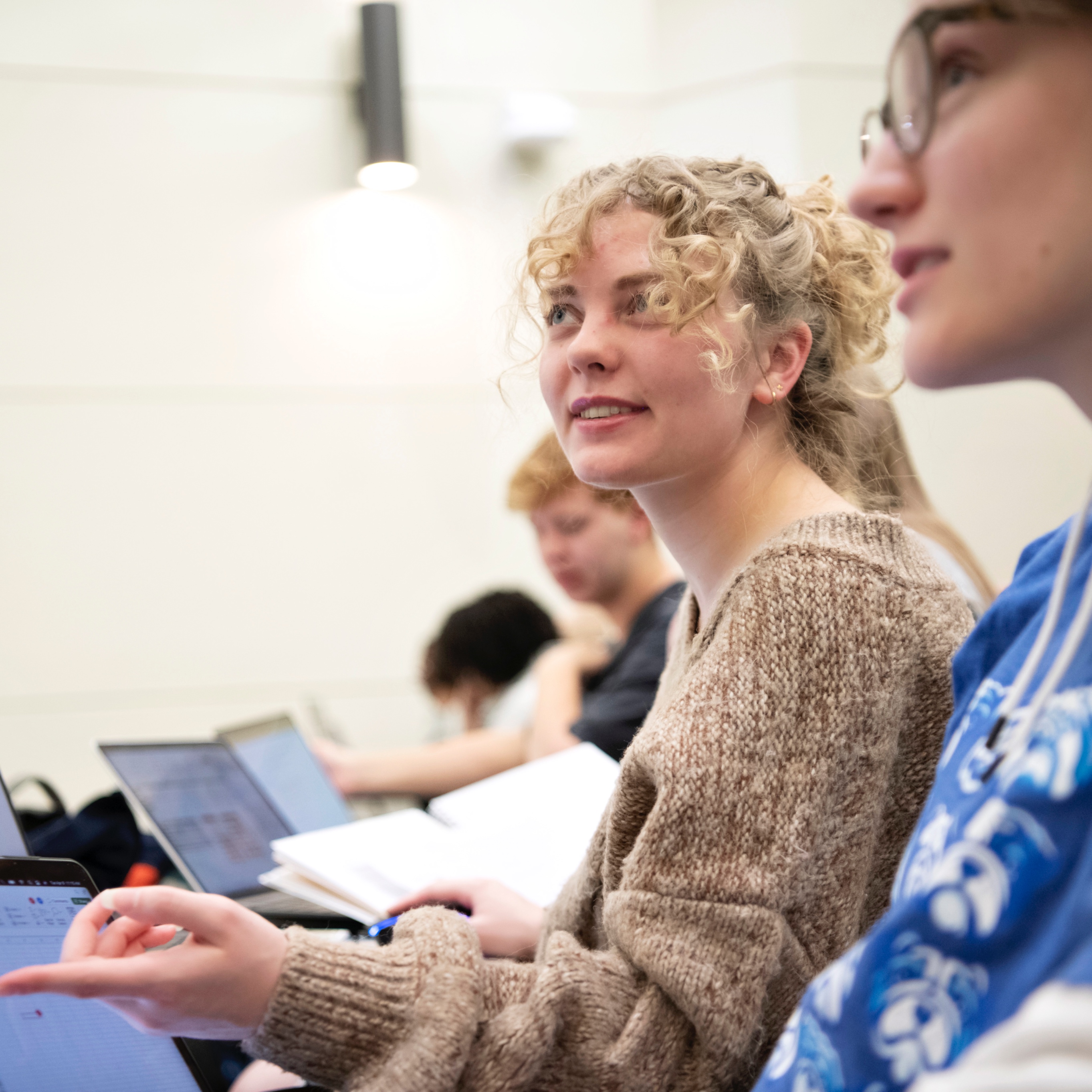 Drake Health Sciences students with laptops listen and engage with a classroom lecturer