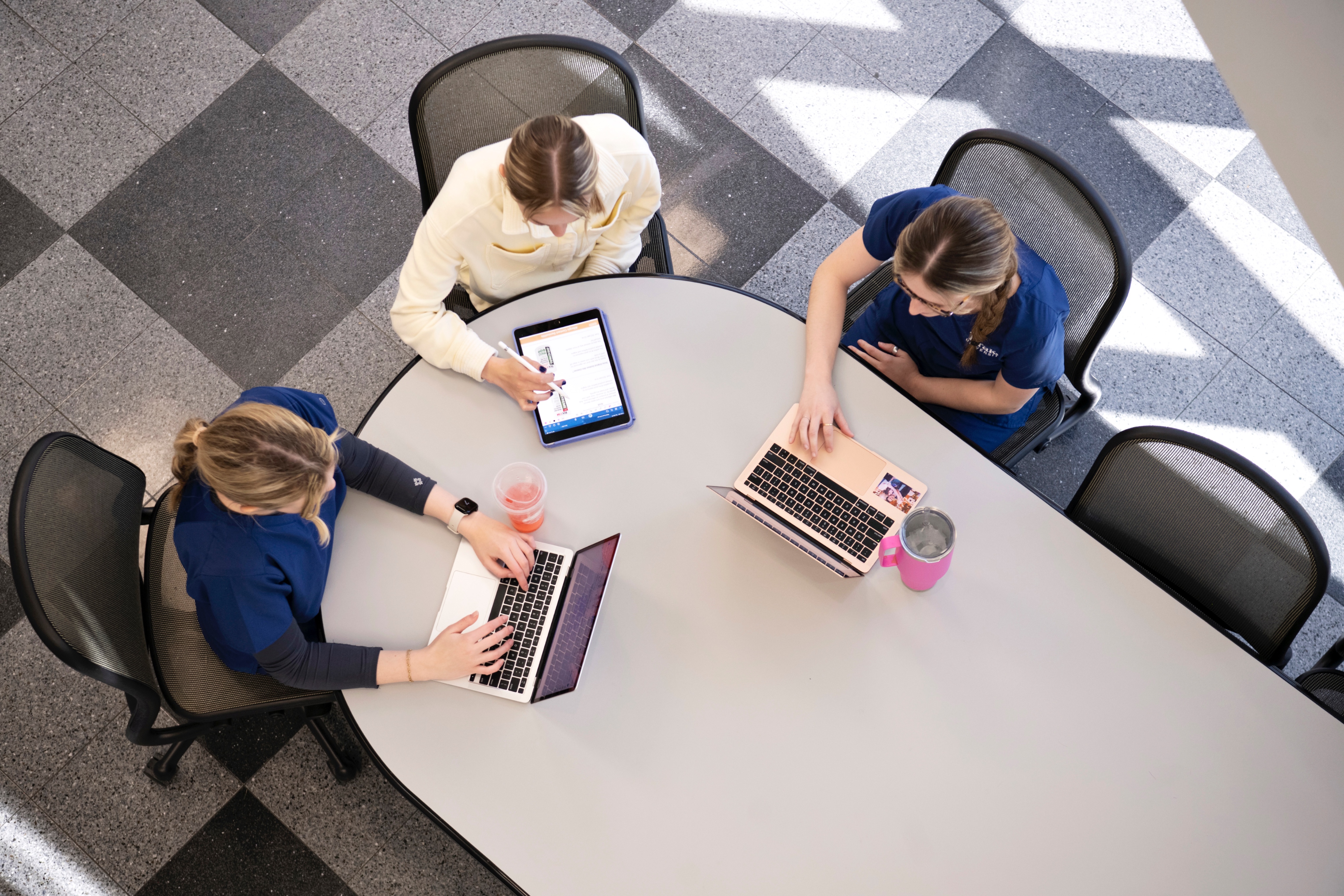 Three Drake Health Sciences Majors study around a table while using their laptops