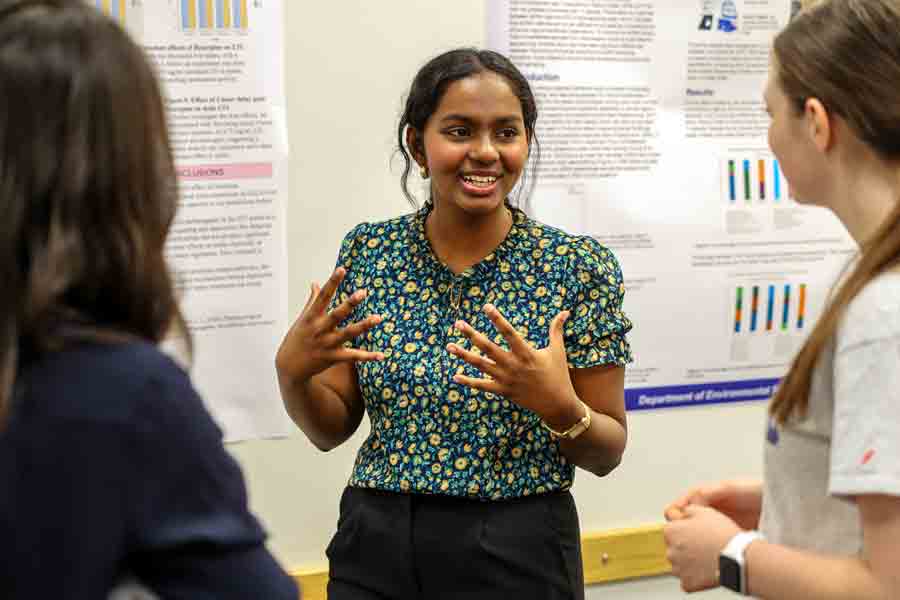 A Drake student explains their history-related research project, standing in front of their posterboard, to onlookers at an undergraduate research symposium on campus