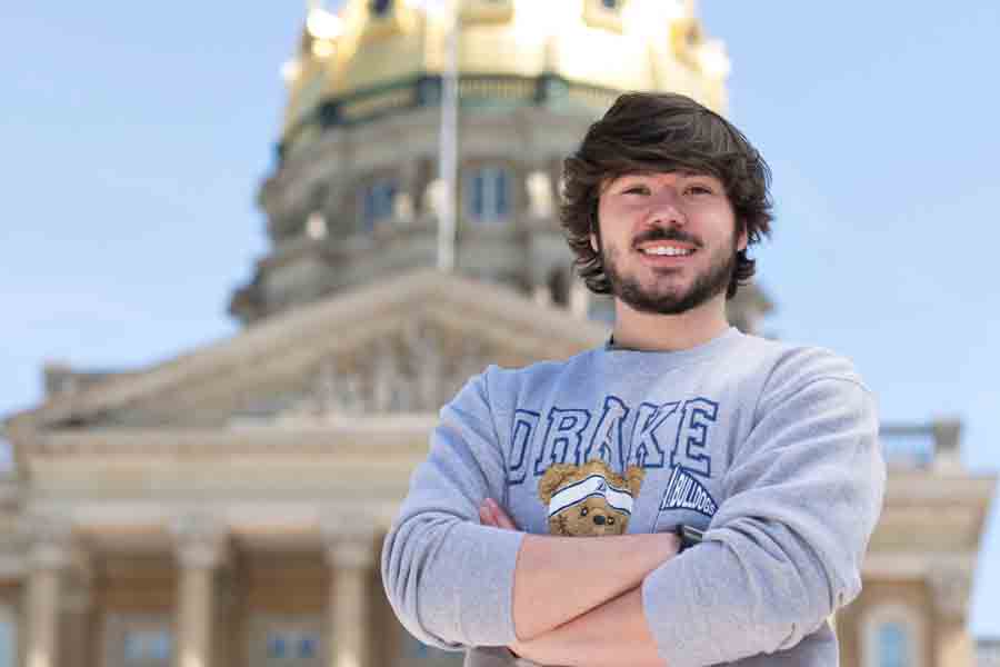 A student in a Drake sweatshirt proudly folds their arms while standing in front of the Iowa Capitol building, a potential internship location for history majors