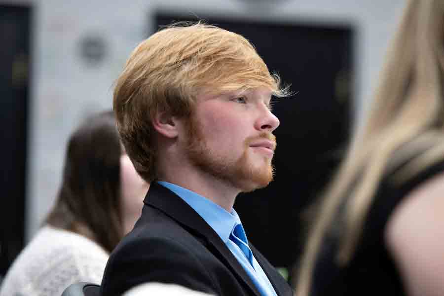A student in a suit and tie focuses during a meeting for a history-related student organization at Drake