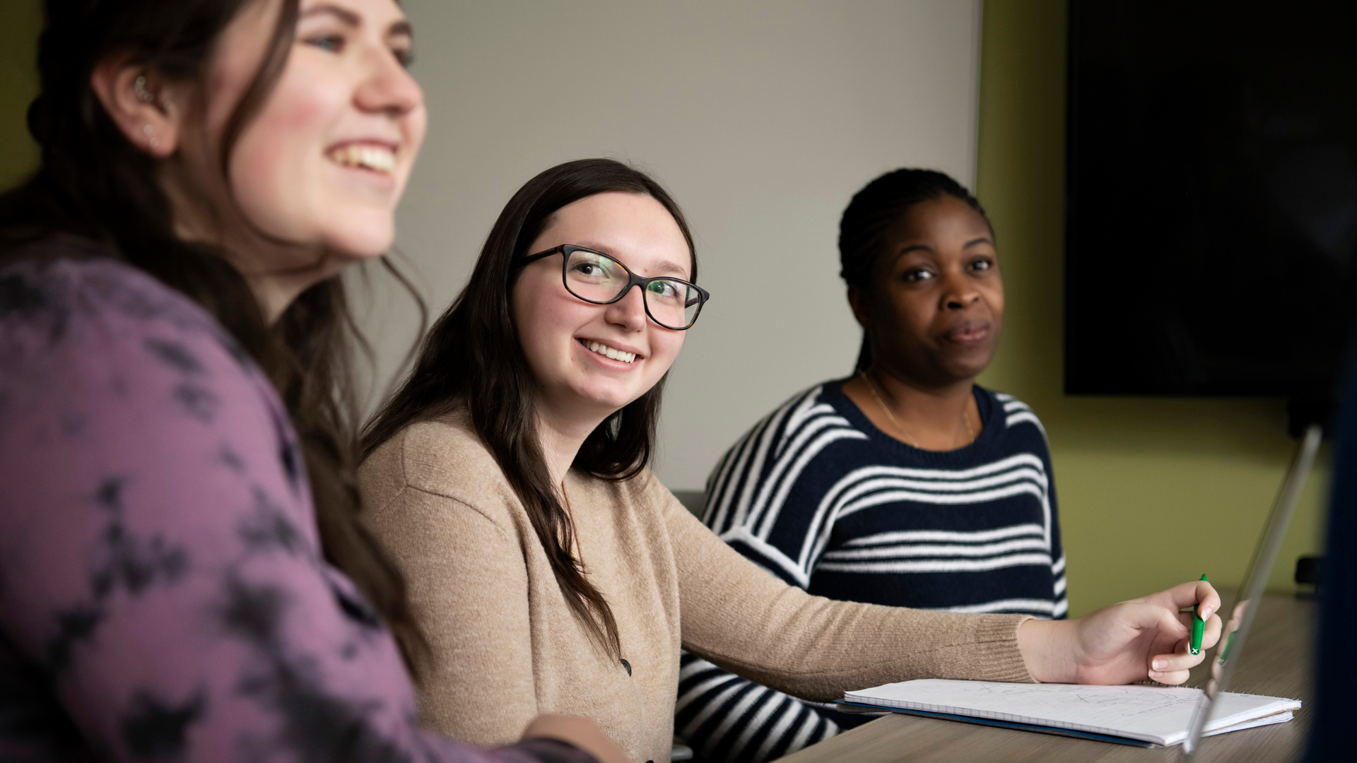 Sitting along a table, three Drake University students attend a class for the Human Resources Management Concentration