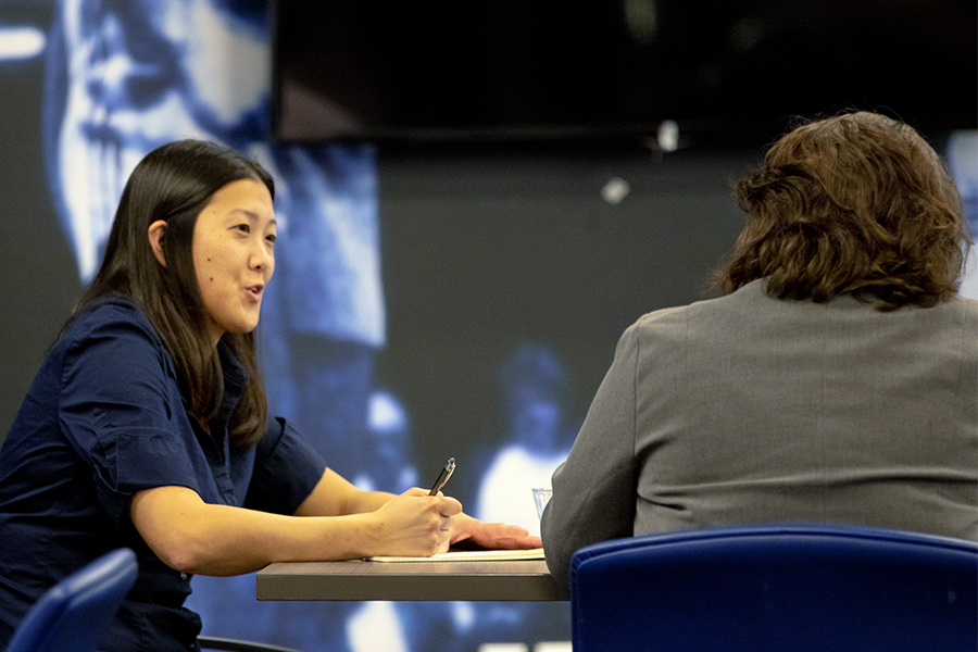 Two participants in Drake's Wellmark BlueX: Technology Applied Learning Program take notes while sitting near a large screen