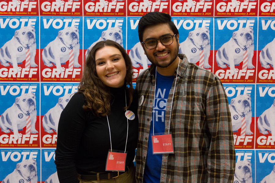 Two Drake International Relations students stand in front of a wall printed with "Vote Griff."