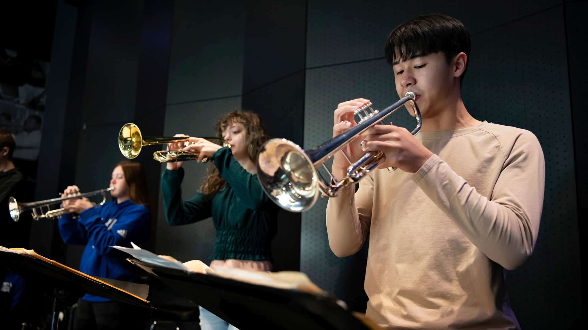 Playing trumpets, Drake Jazz Studies students record a composition in a campus recording studio