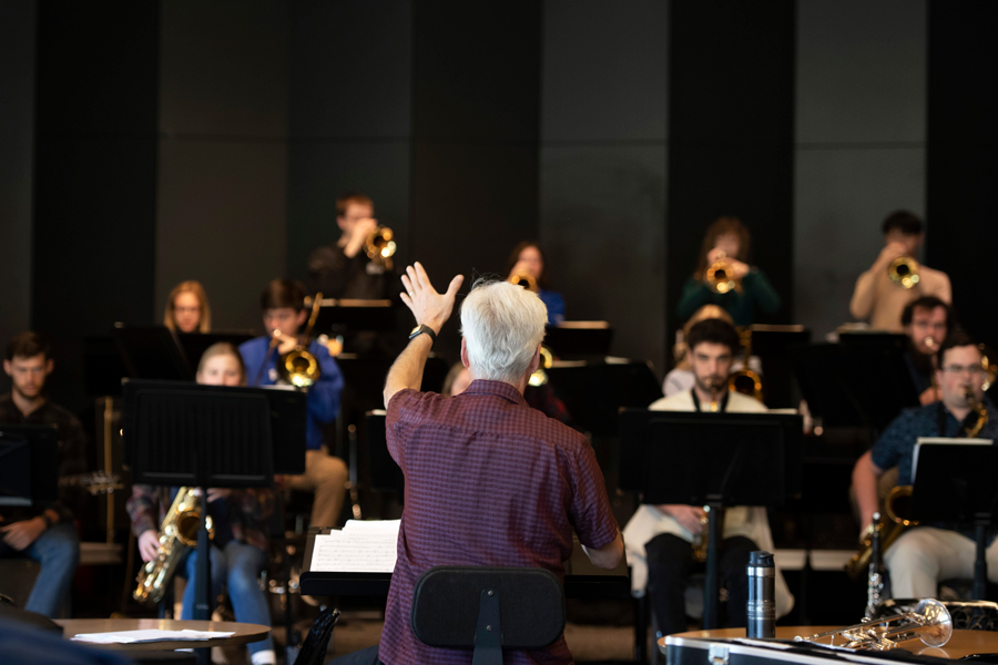 A guest conductor directs an ensemble of brass and wind players at Drake, an opportunity for Jazz Studies students
