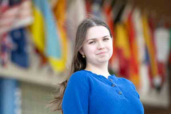 A student stands in front of Drake's Zimpleman College of Business, which features international flags on the exterior